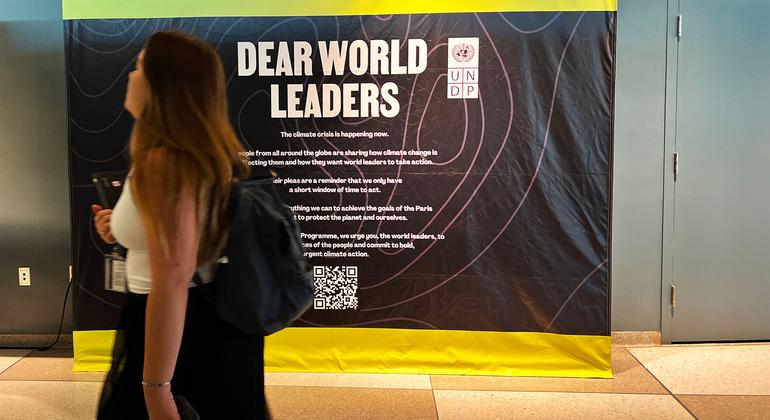 A UN staff member passes in front of a sign calling on world leaders to commit to ‘bold, urgent climate action.’